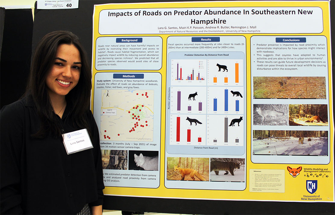 A photo of COLSA student Lara Santos standing in front of her poster presentation at the 2022 Undergraduate Research Conference