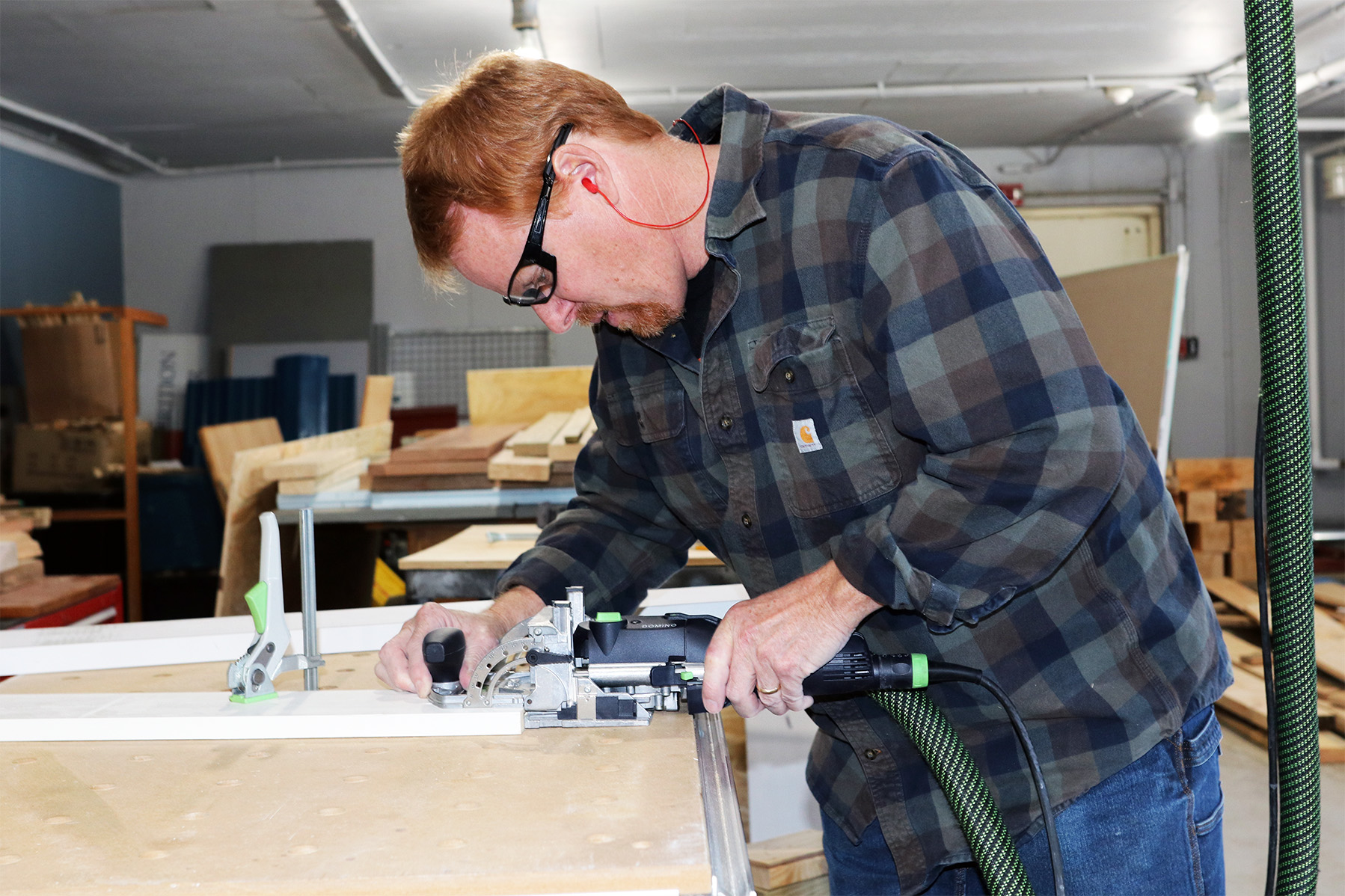 A photo of carpenter Curtis Johnson working with a router on a piece of wood at the UNH Durham campus