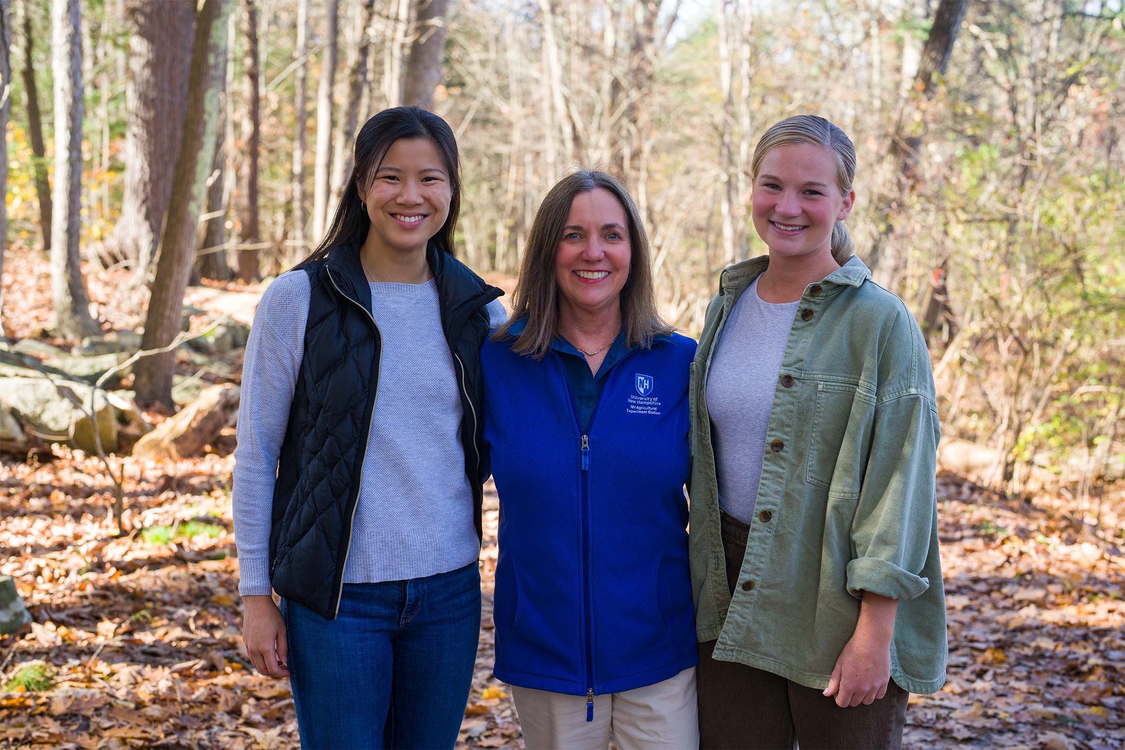 COLSA’s St. Martin Career Exploration Office donor Christine Carberry ’82 (located center) stands with two students in UNH's College Woods.
