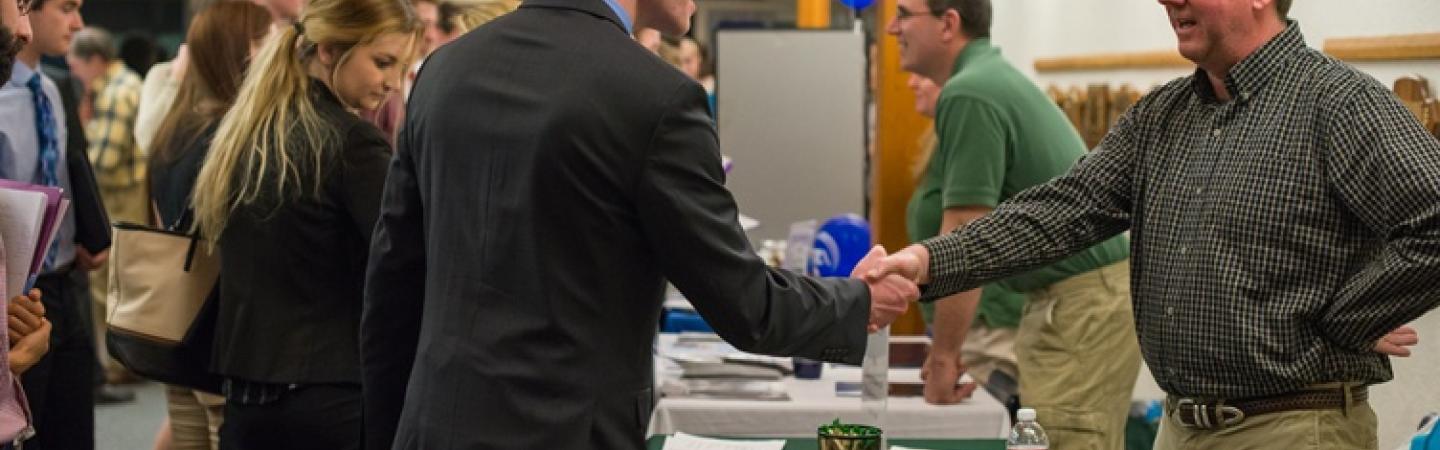 Student shaking hands with a vendor at a career fair