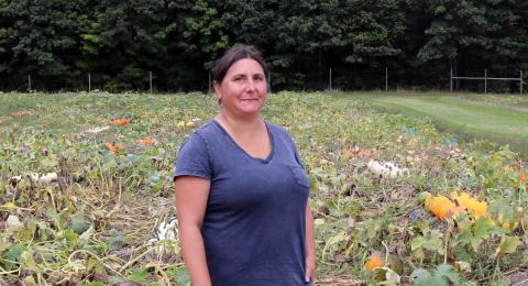 A photo of NHAES scientist Renee Goyette standing in a pumpkin patch at UNH's Kingman Farm