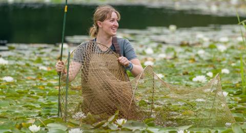 student in marsh with net