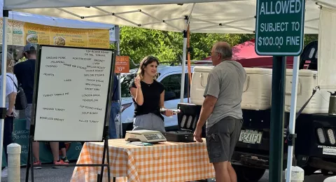 Olivia Audet talks with vendor at a New Hampshire farmer's market