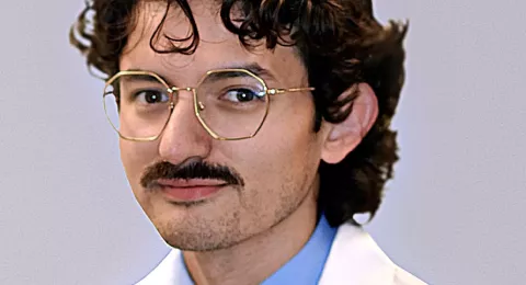 UNH alumni Christopher Martinez poses in his medical school white coat