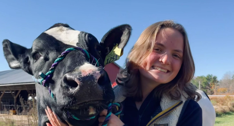 UNH veterinary technology student Madeline Mailhot stands next to a cow