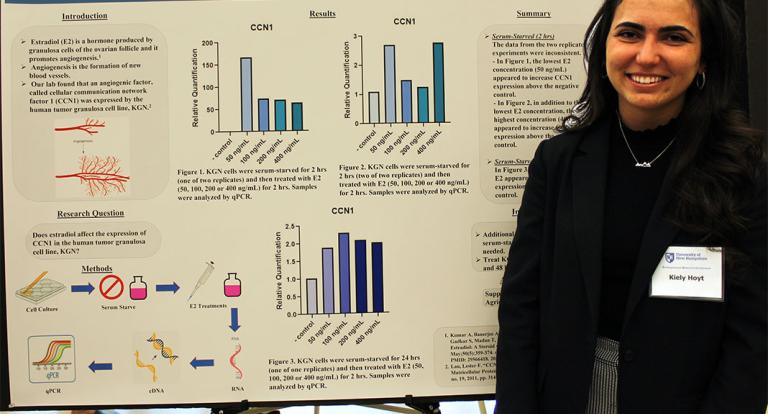 A photo of COLSA student Kiely Hoyt at the 2022 Undergraduate Research Conference in front of her poster presentation