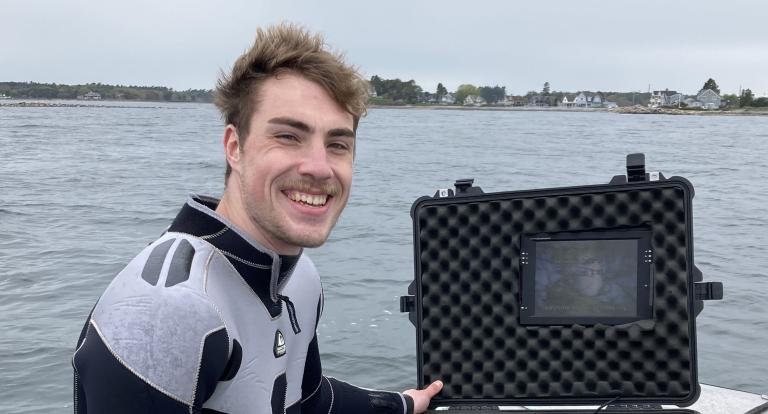 A photo of Biological Sciences graduate student Grant Milne in diving gear out on NH's Great Bay Estuary