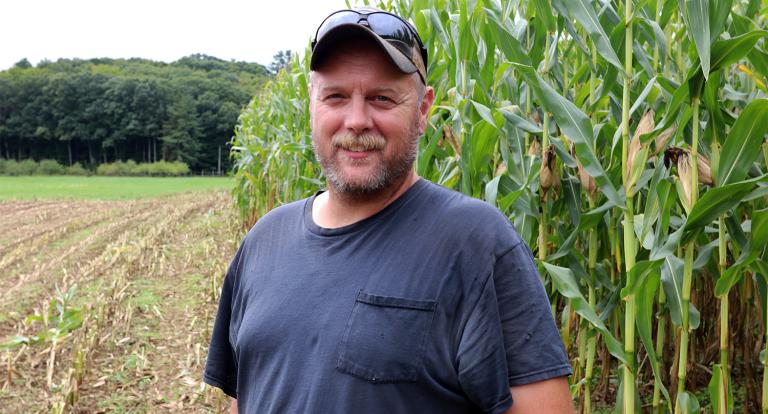 A photo of UNH lead farmer Terry Bickford with corn in the background at Kingman Research Farm.