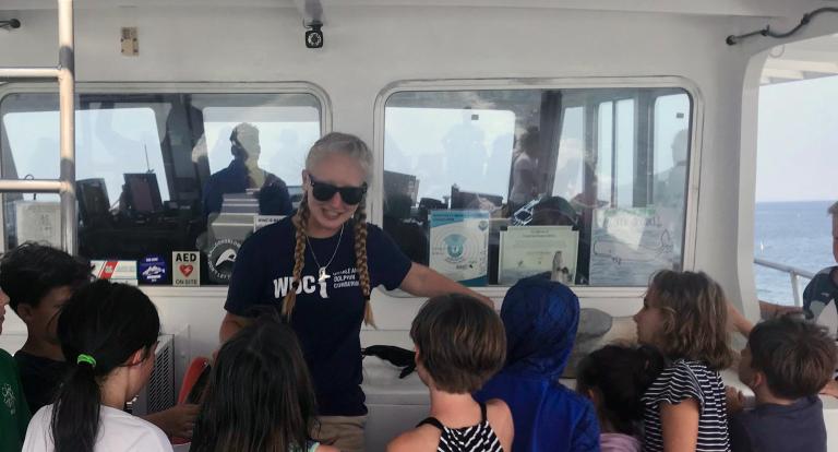 UNH marine, estuarine and freshwater biology major Marissa Cartee '21 talks to children during a whale watch