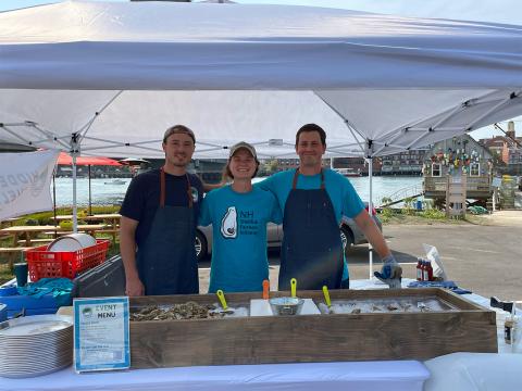 COLSA graduate student Kelsey Meyer (center) with two oyster farmers at an event with Hidden Coast Shellfish.