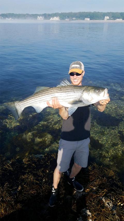Farm Services Manager Pete Davis holding up a striped bass that he caught.