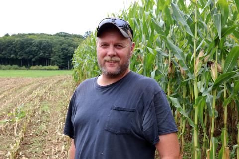 A photo of UNH lead farmer Terry Bickford with corn in the background at Kingman Research Farm.