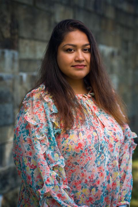 Master of Science in Agricultural Sciences student Tamanna Islam. Tamanna has lightish-brown skin and medium-brown hair. She wears a multi-colored floral print top with bits of red, pink, yellow and light green and blue in it.