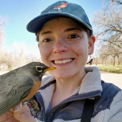 A photo of Karina Sanchez, postdoctoral researcher, holding a bird.