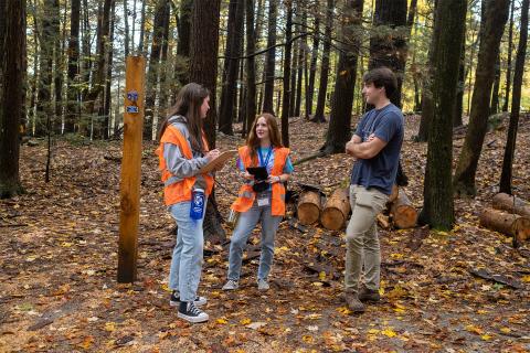 A group of students survey a person to learn about biodiversity and wellness in UNH's College Woods