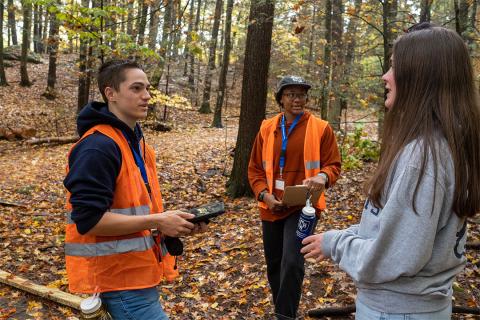 A group of students practice their surveying skills in UNH's College Woods