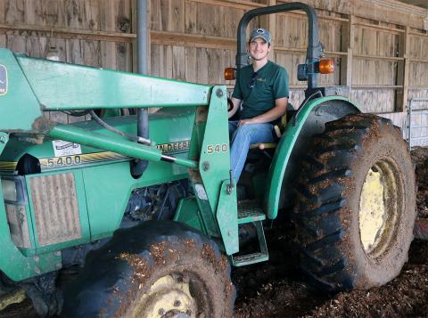 A photo of farm worker Luke Pacchioli driving a tractor at the UNH Organic Dairy Research Farm.