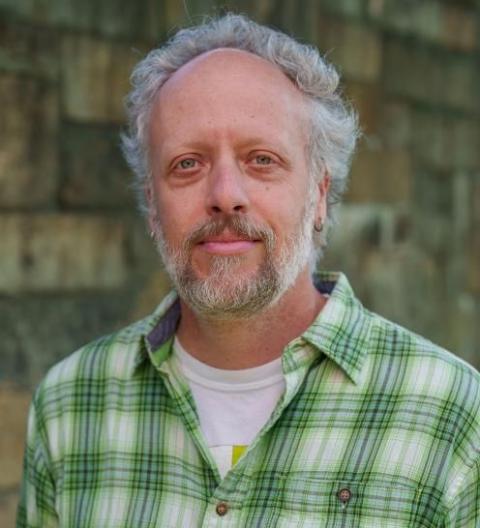A photo of UNH researcher Iago Hale. Iago is a white male with gray hair and beard wearing a green shirt.