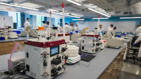 An image of a lab at UNH with equipment on lab benches and researchers wearing lab coats in the background.