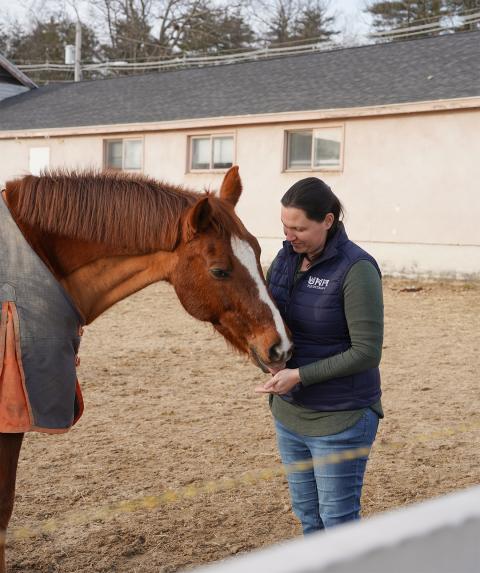 UNH Equine Center manager Erin Morgan-Paugh feeds a horse