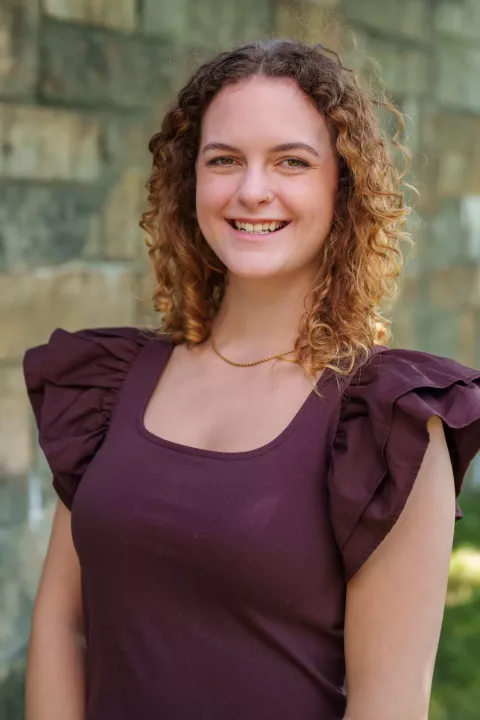 UNH nutrition and dietetics graduate student Elizabeth Barton poses by stone wall