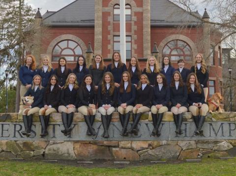 UNH 2024 Intercollegiate Horse Show Association Team poses together on the stone wall in front of Thompson Hall