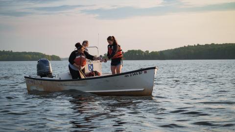 An image of researchers in a boat in great bay estuary inspecting a water sample