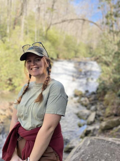 A photo of graduate student Lauren George standing in front of a waterfall