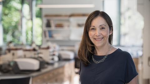 An image of UNH alum marcia haigis standing in her home.