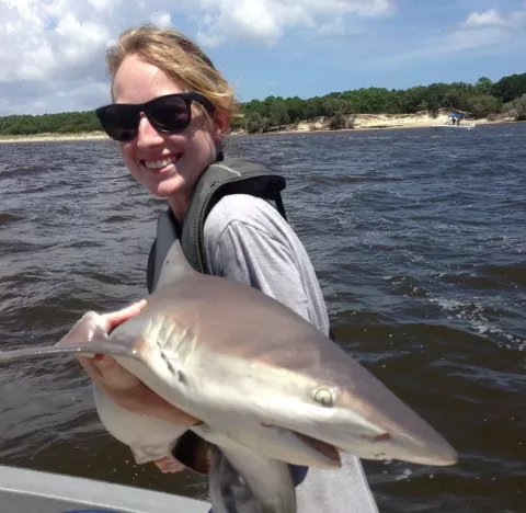 UNH graduate student Maureen Madray on a boat holding a shark