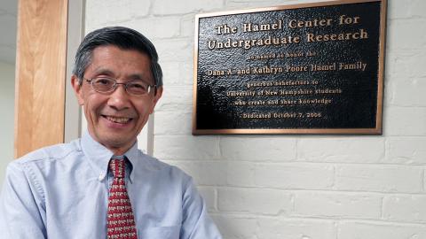 An image of a man standing next to a plaque on a wall