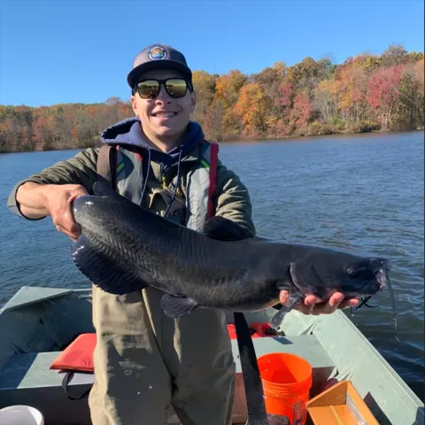 UNH grad student Ryan Adams on a boat holding a fish