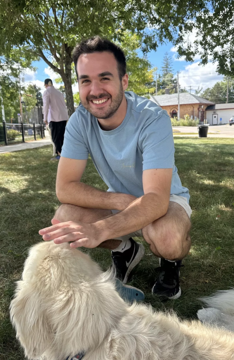 UNH undergraduate Braden Foulks petting a dog near the UNH Dairy Bar