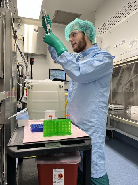 UNH graduate student Nicholas Zylinski in a lab checking a glass tube for residue