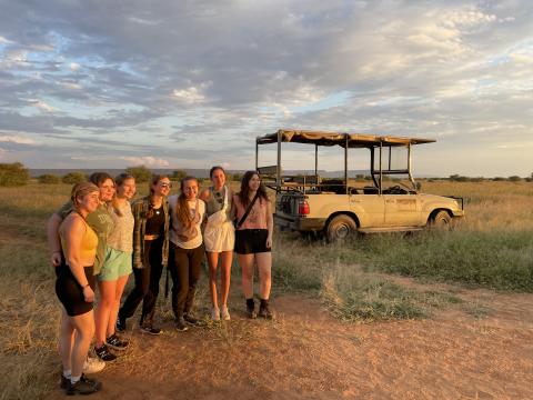 Seven students in the open grasslands of Namibia posing next to a pick-up truck