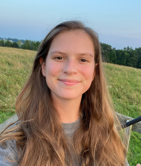 UNH graduate student Megan Graham poses outside with green field behind her