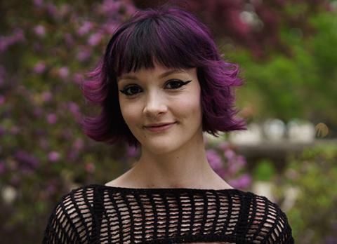 UNH student Liv Syriac poses outside in open knit black sweater