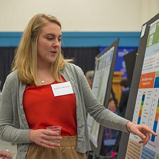Student pointing at her poster at the Undergraduate Research Conference