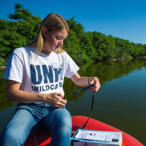 Student taking measurements of lake water