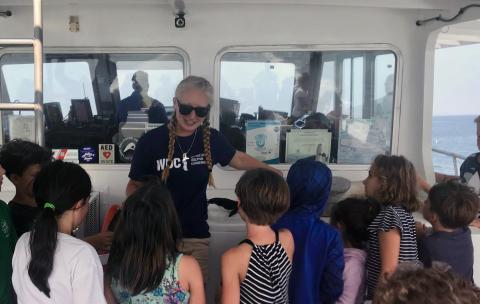 UNH marine, estuarine and freshwater biology major Marissa Cartee '21 talks to children during a whale watch