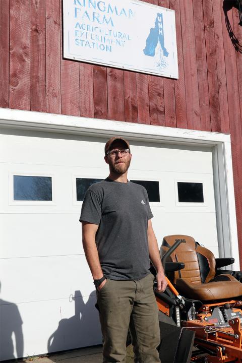 A photo of UNH's Mark Trabold in front of the Kingman Farm Research sign.