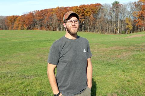 Mark Trabold, assistant farm manager, standing in front of a row of trees at Kingman Research Farm