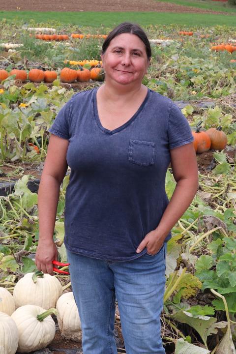A photo of Renee Goyette standing in a pumpkin field.