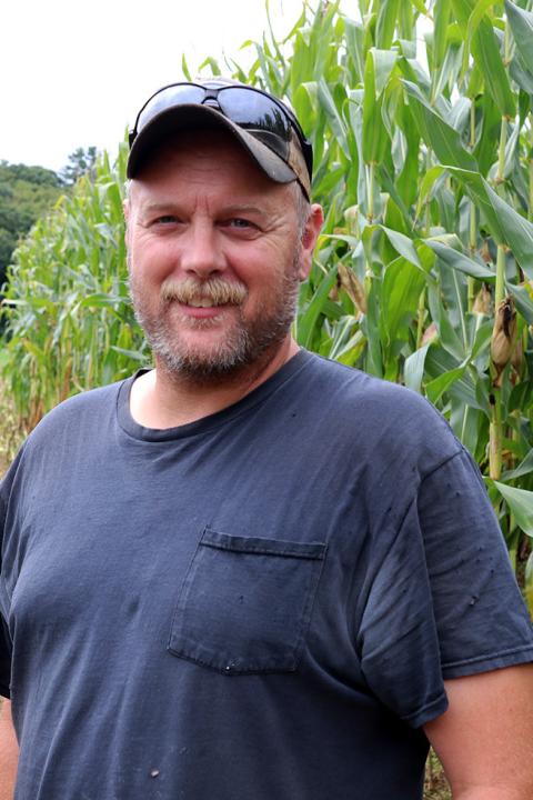 A photo of lead farm services manager Terry Bickford in front of a cornfield.